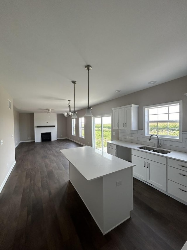 kitchen featuring white cabinetry, sink, backsplash, and a center island