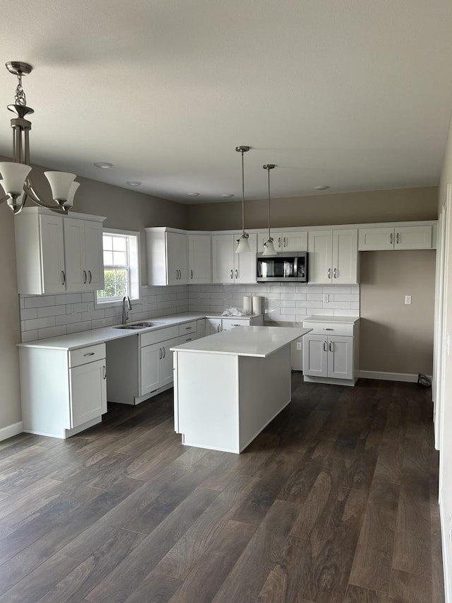 kitchen featuring dark hardwood / wood-style flooring, decorative light fixtures, sink, white cabinetry, and a center island