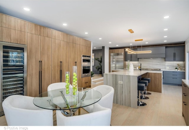 dining area featuring light wood-type flooring, beverage cooler, and sink