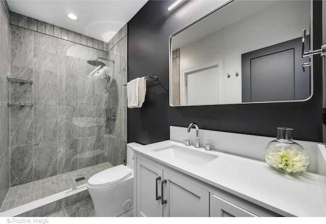 bathroom featuring tiled shower, toilet, and vanity