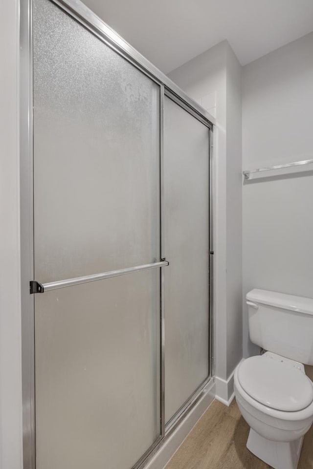 bathroom featuring toilet, hardwood / wood-style floors, and a shower with shower door