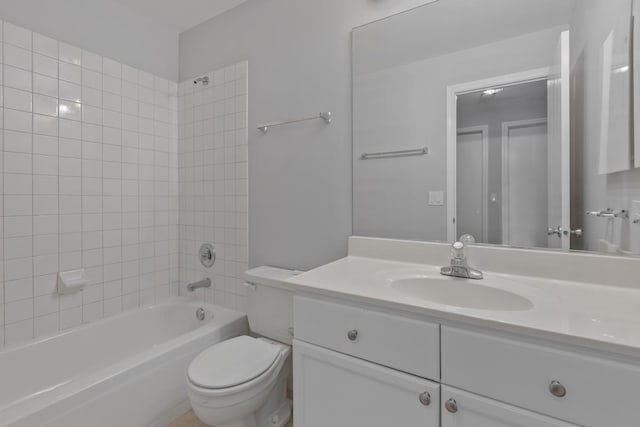 full bathroom featuring tiled shower / bath, vanity, and toilet