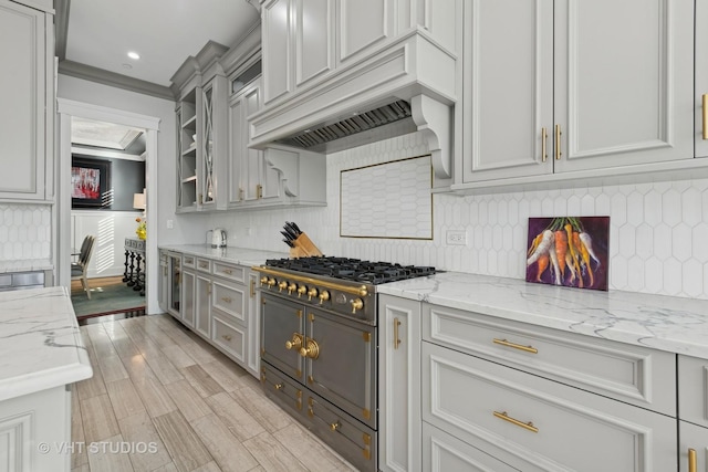 kitchen with tasteful backsplash, ornamental molding, light stone countertops, and custom exhaust hood