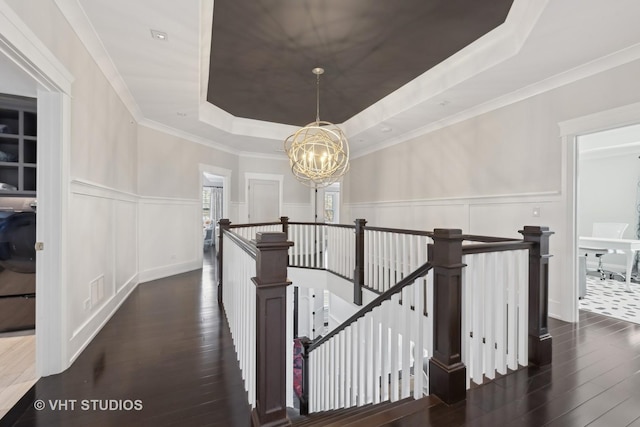 corridor with an inviting chandelier, dark hardwood / wood-style floors, crown molding, and a raised ceiling