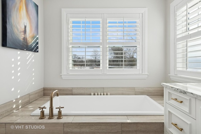 bathroom featuring vanity and tiled tub