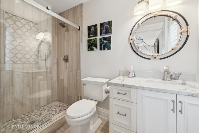 bathroom with a shower with door, vanity, and toilet