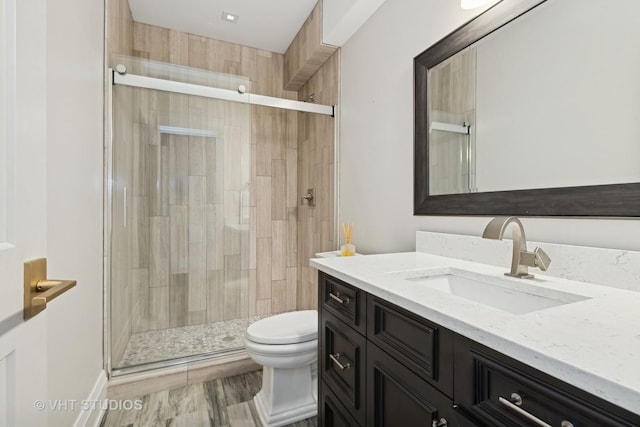 bathroom featuring vanity, toilet, and a shower with shower door