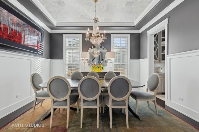 dining room featuring an inviting chandelier, a tray ceiling, dark hardwood / wood-style flooring, and crown molding