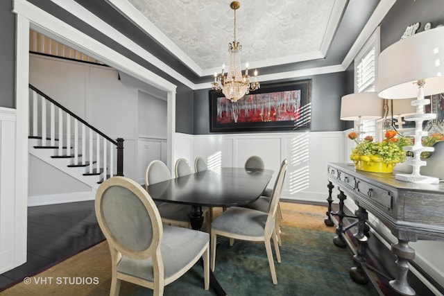 dining space featuring a raised ceiling, crown molding, dark wood-type flooring, and an inviting chandelier