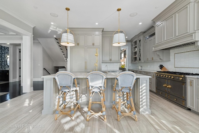 kitchen featuring double oven range, decorative light fixtures, a kitchen bar, and gray cabinetry