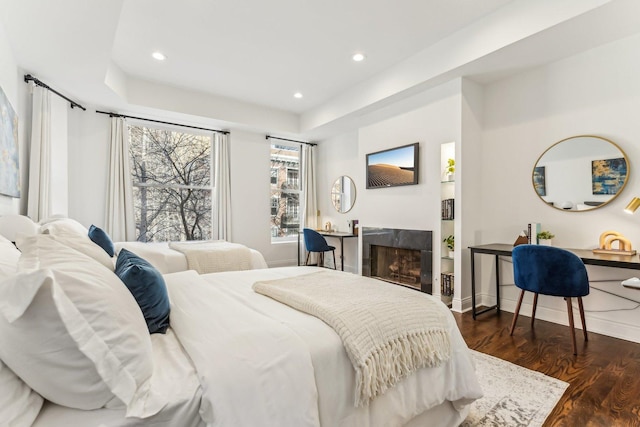 bedroom featuring a high end fireplace and dark hardwood / wood-style floors