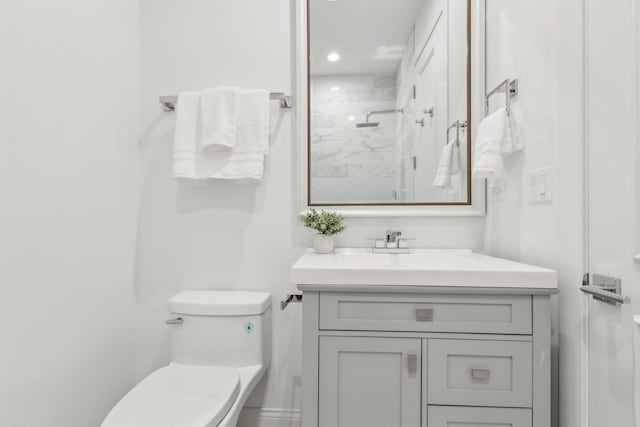 bathroom featuring vanity, toilet, and a shower with shower door