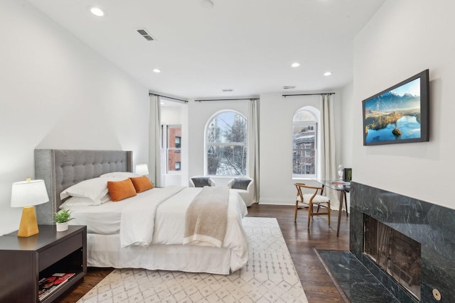 bedroom with dark hardwood / wood-style flooring and a high end fireplace