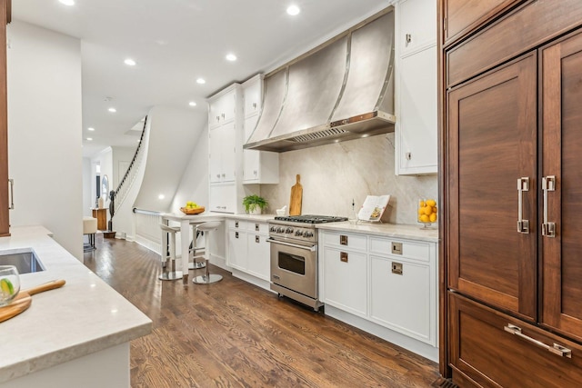 kitchen with dark hardwood / wood-style flooring, custom exhaust hood, high end stove, and white cabinets