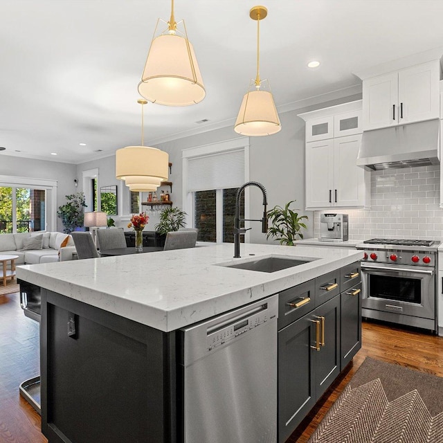 kitchen featuring stainless steel appliances, decorative light fixtures, a kitchen island with sink, and sink