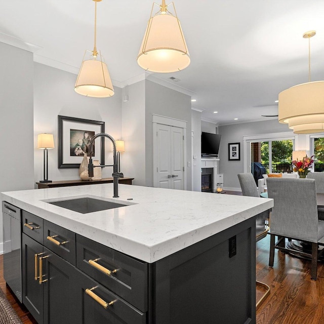 kitchen with sink, hanging light fixtures, a kitchen island with sink, stainless steel dishwasher, and light stone countertops