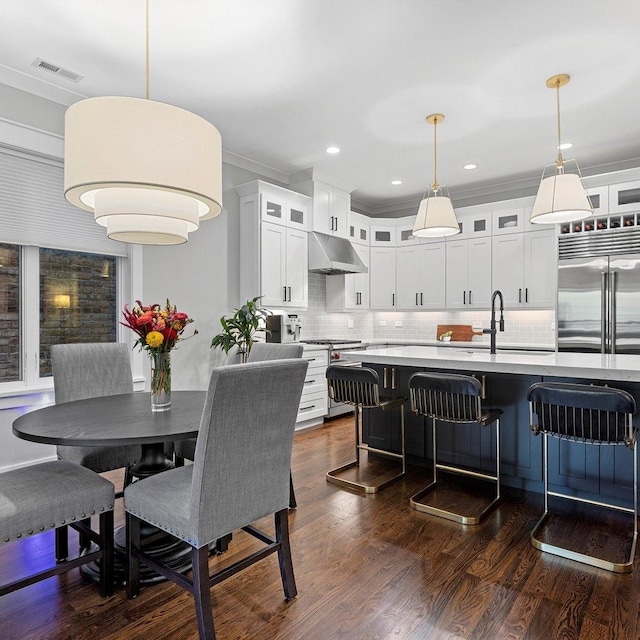 dining space featuring dark wood-type flooring, crown molding, and sink