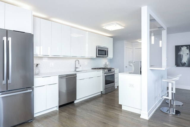 kitchen with dark wood-type flooring, sink, white cabinets, stainless steel appliances, and backsplash