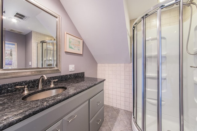 bathroom with lofted ceiling, an enclosed shower, tile walls, vanity, and tile patterned flooring