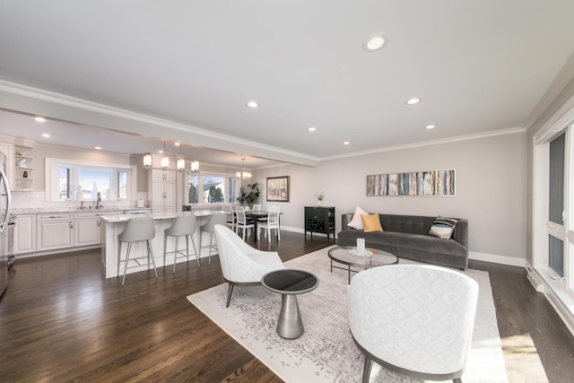 living room featuring ornamental molding, dark wood-type flooring, sink, and an inviting chandelier