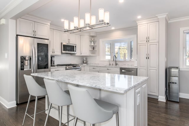 kitchen with appliances with stainless steel finishes, white cabinetry, sink, dark hardwood / wood-style flooring, and a center island