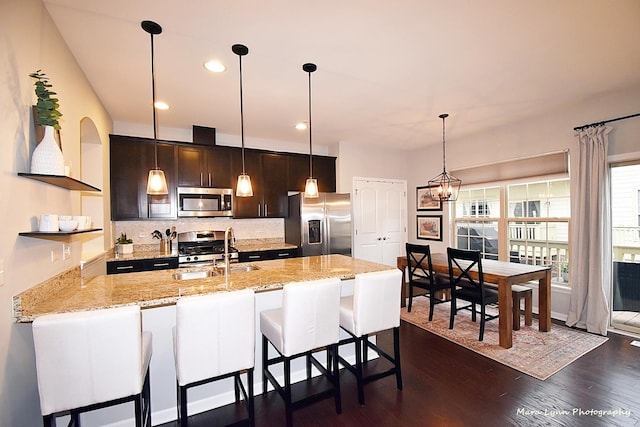 kitchen featuring stainless steel appliances, sink, backsplash, dark hardwood / wood-style floors, and light stone counters