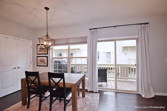 dining area with plenty of natural light, dark hardwood / wood-style floors, and an inviting chandelier