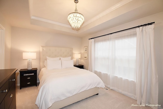 carpeted bedroom with multiple windows, a tray ceiling, crown molding, and a notable chandelier