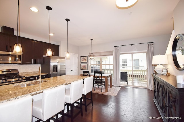 kitchen featuring dark brown cabinets, stainless steel appliances, a kitchen bar, and dark wood-type flooring