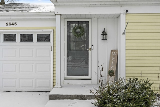 snow covered property entrance with a garage