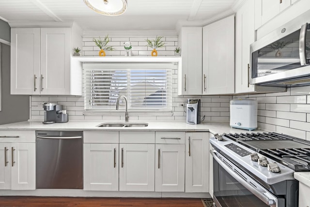 kitchen featuring stainless steel appliances, sink, decorative backsplash, and white cabinets