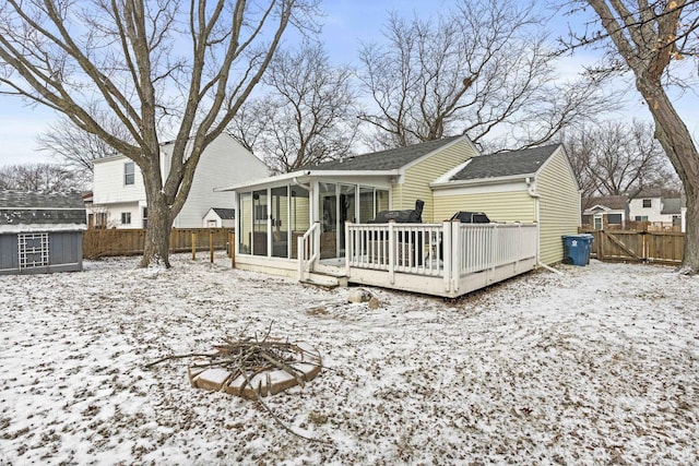 snow covered property featuring an outdoor fire pit, a deck, and a sunroom