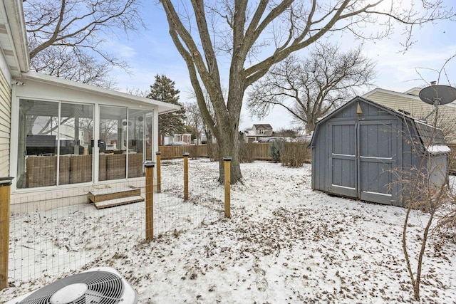 yard layered in snow with central AC and a sunroom