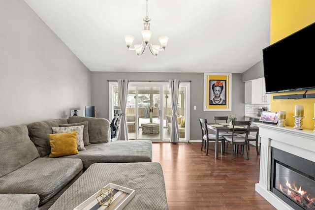 living room with dark wood-type flooring, a chandelier, and vaulted ceiling