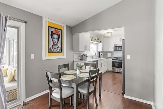 dining room featuring lofted ceiling, sink, and dark hardwood / wood-style flooring