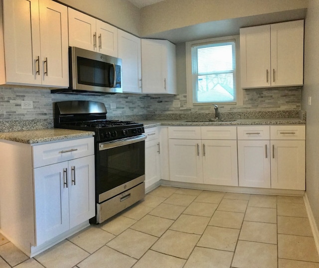 kitchen featuring sink, white cabinetry, light tile patterned floors, and stainless steel appliances