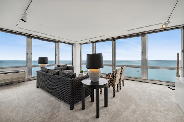 sunroom / solarium with rail lighting, a water view, and a wall mounted air conditioner