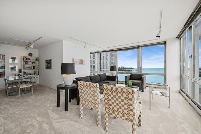 living room featuring track lighting, light carpet, a water view, and floor to ceiling windows