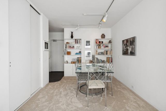 dining space with rail lighting and light carpet