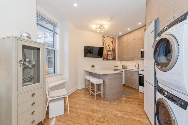 laundry room featuring sink, light hardwood / wood-style flooring, and stacked washing maching and dryer