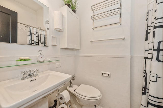 bathroom with sink, toilet, and tile walls