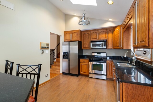 kitchen with sink, stainless steel appliances, light wood-type flooring, and lofted ceiling