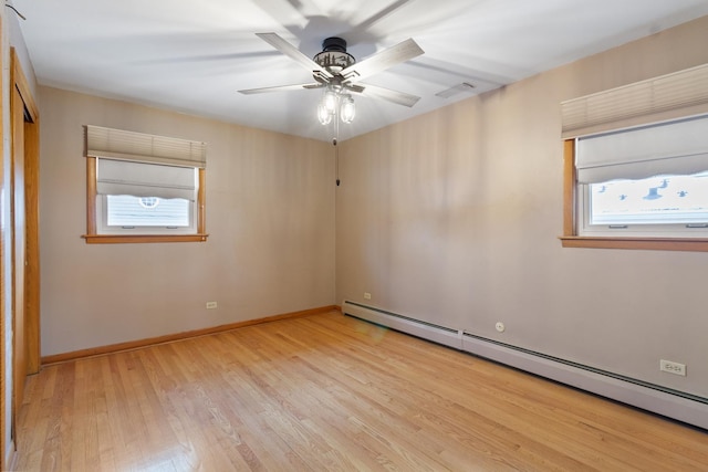 spare room with ceiling fan, baseboard heating, and light hardwood / wood-style flooring