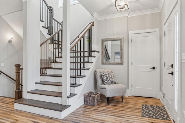 stairway with wood-type flooring and ornamental molding