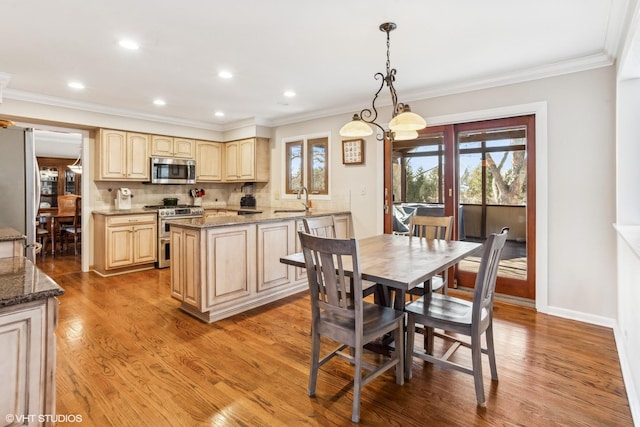 dining space featuring sink, crown molding, an inviting chandelier, and wood-type flooring