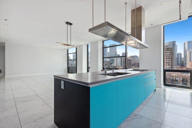 kitchen with sink, a wealth of natural light, and a kitchen island with sink