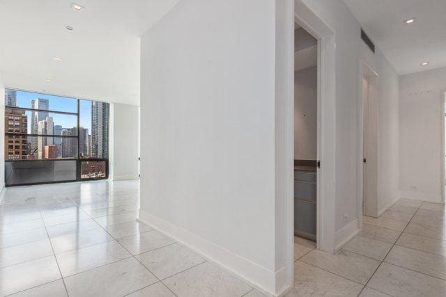 hall featuring light tile patterned floors and floor to ceiling windows