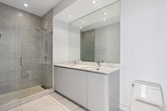 bathroom with vanity, toilet, a shower with door, and tile patterned flooring