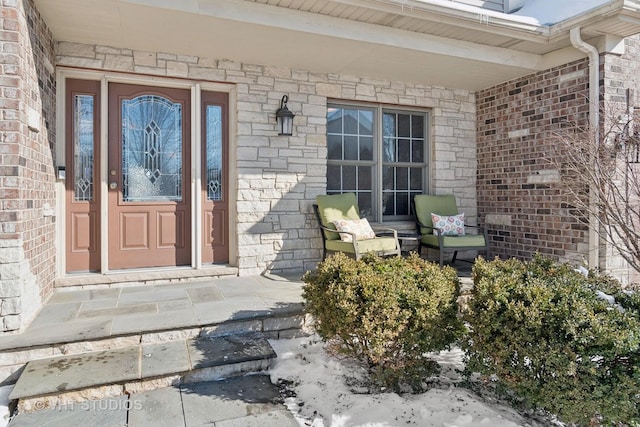 doorway to property featuring a porch and brick siding