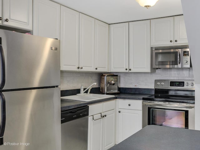 kitchen featuring dark countertops, appliances with stainless steel finishes, white cabinets, and a sink